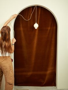 a woman is hanging something on the wall with a lamp attached to it's side