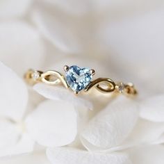 a ring with a blue topazte surrounded by white flowers on a white flower