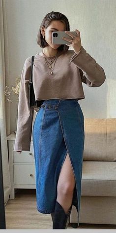 a woman taking a selfie in front of a mirror wearing a blue denim skirt