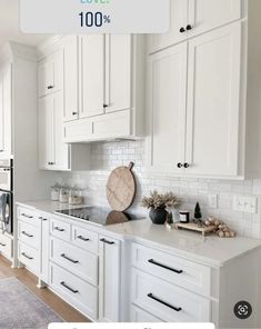 a kitchen with white cabinets and countertops has a large wooden cutting board on the island