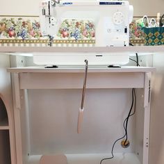 a sewing machine sitting on top of a white table next to a shelf filled with other items