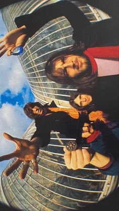 a group of people standing next to each other in front of a building with the sky behind them