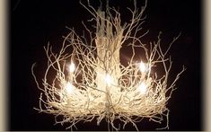 a chandelier made out of branches with lit candles