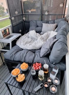 a bed sitting on top of a wooden floor next to a table filled with food