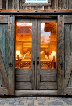 two wooden doors that are open with lights on them in front of a barn style building