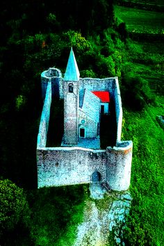 an aerial view of a castle in the middle of a field with trees around it