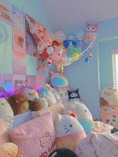 a bunch of stuffed animals that are laying on a bed in a room with blue walls