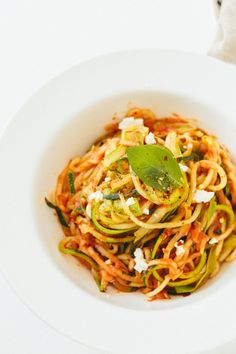 a white bowl filled with spaghetti and vegetables