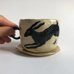 a hand holding a coffee cup with an image of a running rabbit on the side