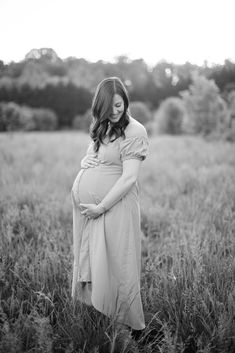 a pregnant woman is standing in a field