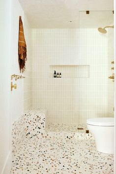 a white tiled bathroom with a toilet and shower