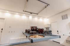 a drum set is suspended from the ceiling in a room with white walls and flooring