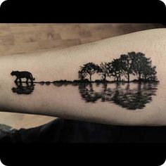 a man's arm with an elephant and trees on it