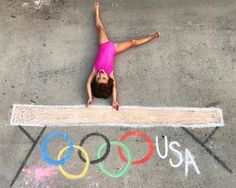 a woman in pink shirt laying on the ground next to chalk writing that says usa