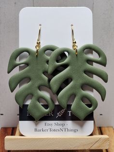 the earrings are made out of clay and have green leaves on them with gold ear wires