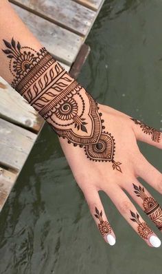 a woman's hand with henna tattoos on it