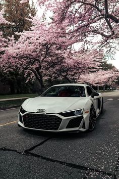 a white car parked in front of pink flowers