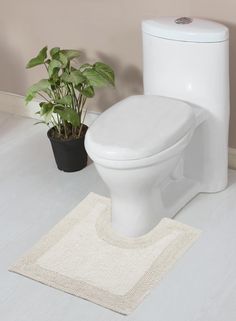 a white toilet sitting next to a potted plant on top of a bathroom floor