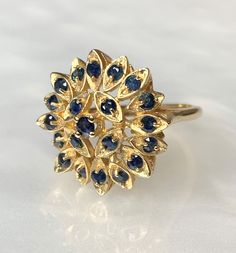 "Sapphire Ring, Blue Sapphire Ring, Sapphire Ring for Women, Sapphire Sunburst Ring, Vintage Sapphire Jewelry, Vintage Gold Ring, OOAK Ring A beautiful and intricately detailed never before owned vintage 14k yellow gold \" Sunburst\" ring featuring approximately 0.80 carats of round sapphires set within marquise shaped \"rays\". *Approximate ring weight: 6.19 grams * Ring size: 6 3/4 * Complimentary resizing is available up to 3 sizes larger or smaller than stated size." Cluster Yellow Gold Sapphire Ring, Cluster Sapphire Ring In Yellow Gold, Yellow Gold Sapphire Cluster Ring, Yellow Gold Cluster Sapphire Ring, Yellow Gold Sapphire Cluster Ring With Center Stone, Yellow Gold Cluster Sapphire Ring With Center Stone, Fine Jewelry Sapphire Ring With 17 Jewels, Yellow Gold Multi-stone Cluster Sapphire Ring, Yellow Gold Cluster Multi-stone Sapphire Ring