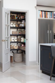 an open pantry in the middle of a kitchen with lots of shelves and baskets on it