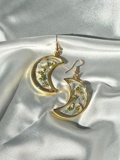 Unique Handmade Pressed Flower Crescent Moon Earrings - Artistic Craftsmanship in Silver Crafted with meticulous attention to detail, this Crescent Moon Earrings set is a true work of art. Here's a glimpse into the process: Flower Selection: Hand-selected flowers are carefully pressed and preserved to capture their natural beauty. Resin Perfection: After drying, the flowers are encased in a slow-cured resin for clarity and durability. Each piece undergoes a meticulous finishing process to addres Whimsical Gold Jewelry For Pierced Ears, Whimsical Gold Jewelry For Mother's Day, Whimsical Gold Earrings With Moon Charm, Whimsical Gold Moon Jewelry, Whimsical Moon-shaped Gold Jewelry, Handmade Moon Shaped Artistic Jewelry, Handmade Moon-shaped Artistic Jewelry, Handmade Artistic Moon-shaped Jewelry, Unique Moon Charm Earrings As Gift