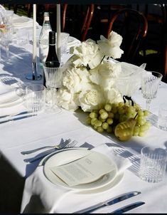 the table is set with white flowers and silverware, wine glasses, and napkins