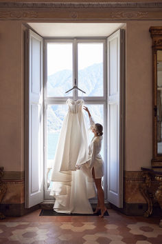 a woman standing in front of a window next to a dress