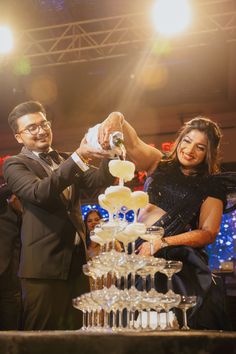 a man and woman standing next to each other in front of a cake on top of a table