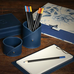 a pen, notebook and pencil holder on a wooden table