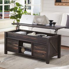 a living room with a couch, coffee table and laptop on top of it in front of a window