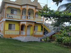 a yellow and white house sitting on top of a lush green field