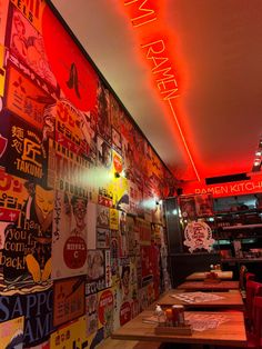 the interior of a restaurant with colorful signs on the wall and wooden tables in front of it