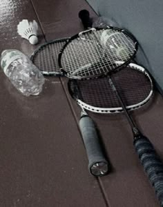 two tennis rackets are laying on the floor next to water bottles and other items