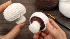 someone is crocheting two small white and brown items together on a wooden table