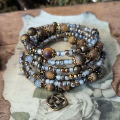 This memory wire bracelet combines matte tiger eye beads in beautiful shades of blue, framed by antique bronze.  ೋღ ↟ ღೋ  ❁ Colors: brown, antique bronze and blue ❁ Pendant: Celtic knot and two small leaf pendants  ೋღ ↟ ღೋ  ➻ Each order is packaged with love and complemented by a handwritten, personal dedication to you before it goes on its journey.🖤 ➻ Your shipment will be insured and sent with tracking so that you can keep an eye on it at all times. ➻ Shipping within Germany: free ➻ Worldwide: €8.99 ➻ only 1 available  ೋღ ↟ ღೋ  So that you can enjoy your piece of jewellery for a long time <3 ❁ Avoid contact with water, perfume and creams. ❁ Clean with a soft, dry cloth. ❁ Store in a dry and protected place, e.g. in a jewelry box ❁ Protect from prolonged and direct sunlight. ❁ Lose weigh Spiritual Wire-wrapped Beaded Bracelets, Memory Wire Rosary Bracelet, Wood Bead Memory Wire Bracelet, Purple Memory Wire Bracelets, Bohemian Multi-strand Wire Wrapped Beaded Bracelets, Stacked Beaded Bracelets, Memory Wire Wrap Bracelets, Blue Pendant, Small Leaf