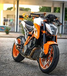 an orange and white motorcycle parked in front of a building