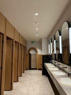 a row of sinks and mirrors in a public restroom with wood paneling on the walls