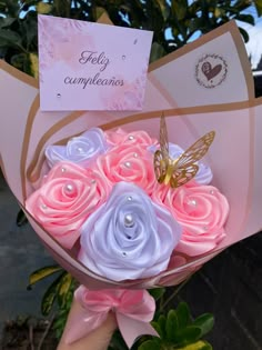 a bouquet of pink and blue flowers with a butterfly on top is held by someone's hand