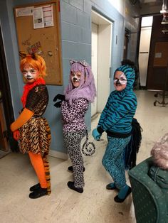 three people in animal costumes standing next to each other with suitcases on the floor