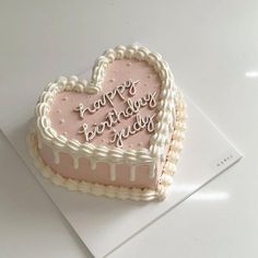 a heart - shaped birthday cake with frosting and icing on a white surface