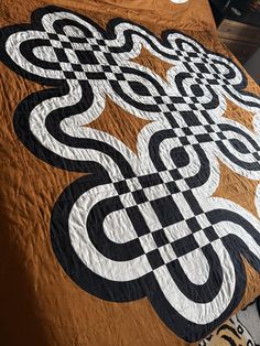 a bed covered in a brown and black quilt with an intricate design on the cover