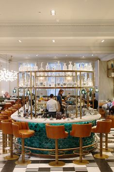 people are sitting at the bar in a fancy restaurant with chandeliers hanging from the ceiling