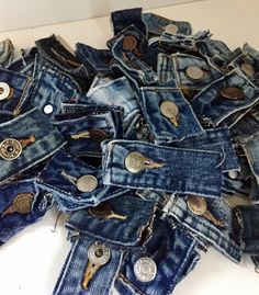 a pile of blue jean pants with buttons on the bottom and one button in the middle