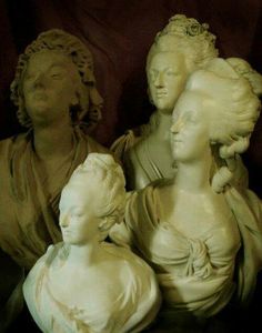 three statues of women sitting next to each other