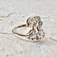 A beautiful vintage 14 karat yellow gold diamond cocktail ring. It centers a marquise diamond weighing approximately 0.30 carat. It is surrounded by 14 round diamonds weighing approximately 0.30 carat The diamonds are approximately G-H in color and VS1 in clarity. Stamped 14K. It weighs 4.6 grams. Size 5.25 US / K UK. > Resizing included. This ring can be resized to fit most fingers. Please contact us for details. Resized rings are final sale. Free resizing does not apply to discounted rings ove Marquise Multi-stone Diamond Ring, Marquise Cut Multi-stone Cubic Zirconia Diamond Ring, Cubic Zirconia Marquise-cut Multi-stone Diamond Ring, Multi-stone Cubic Zirconia Marquise Cut Ring, Classic Marquise Multi-stone Diamond Ring, Marquise Cut Multi-stone Diamond Ring For Anniversary, Classic Multi-stone Marquise Cut Diamond Ring, Classic Diamond Ring With Multi-stone Marquise Cut, Classic Marquise Cut Multi-stone Diamond Ring