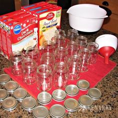 there are many empty glass jars on the counter with one red measuring cup in front of them