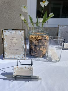 a table topped with two glass vases filled with flowers next to cards and cookies