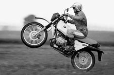 black and white photograph of a person on a motorcycle doing a trick in the air