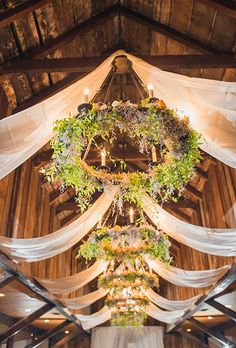 the inside of a wedding venue decorated with greenery and hanging chandelier, draped in white fabric