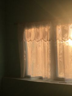 the sun shines through the curtains in this window sill, which is covered with white lace